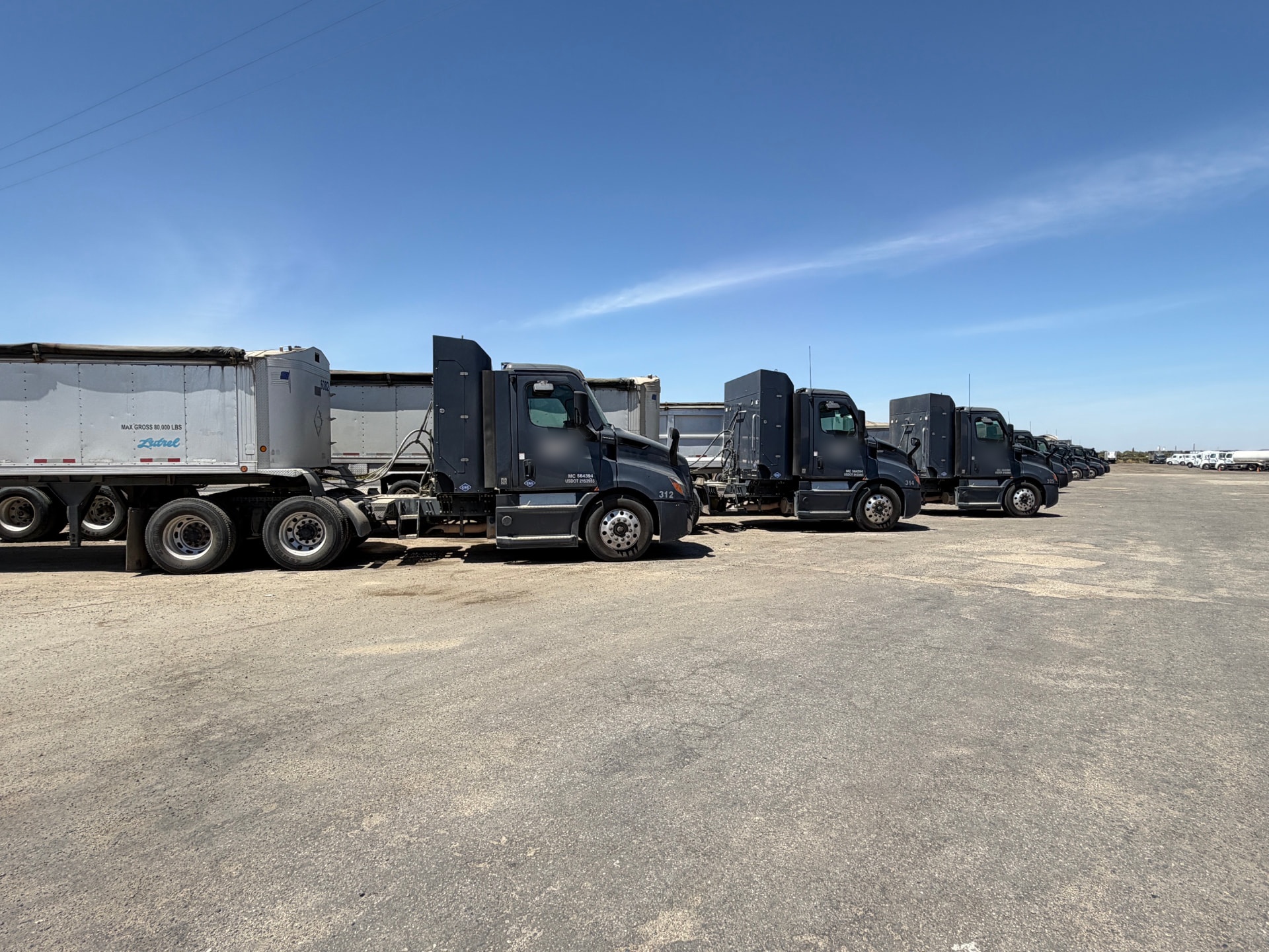 All Seasons Logistics trucks and end-dump trailers lined up in the fleet yard