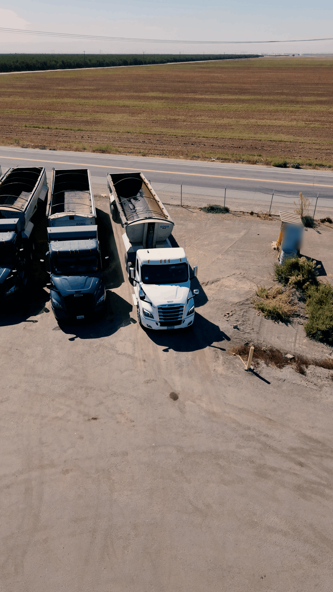 Aerial view of All Seasons Logistics end-dump trucks beside farmland